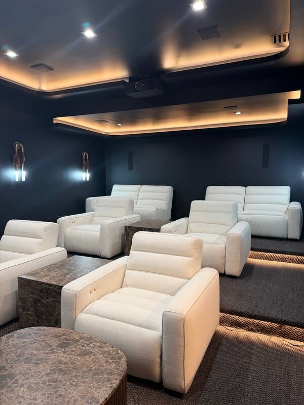 Tiered seating with cove lighting, ceiling projector, and sconces