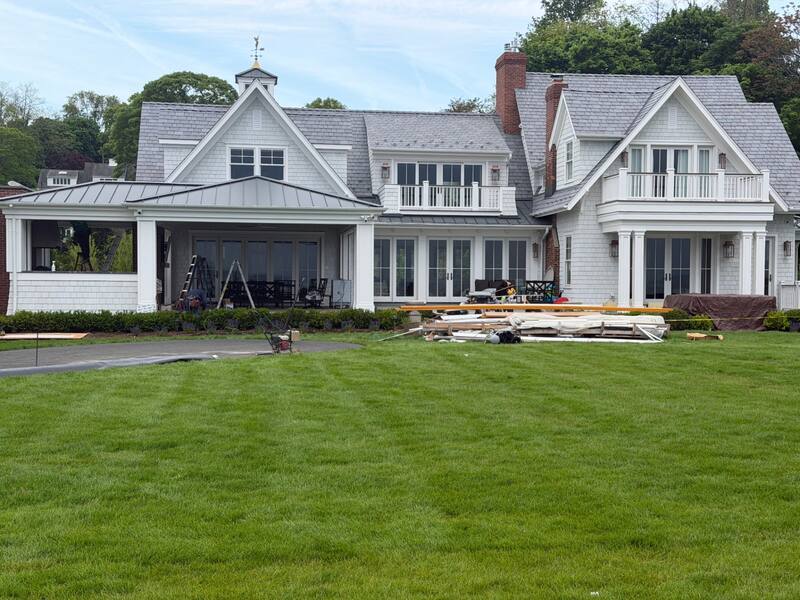 Close-up of the home's rear elevation showing the covered porch and multiple French door openings prepared for motorized screen tracks