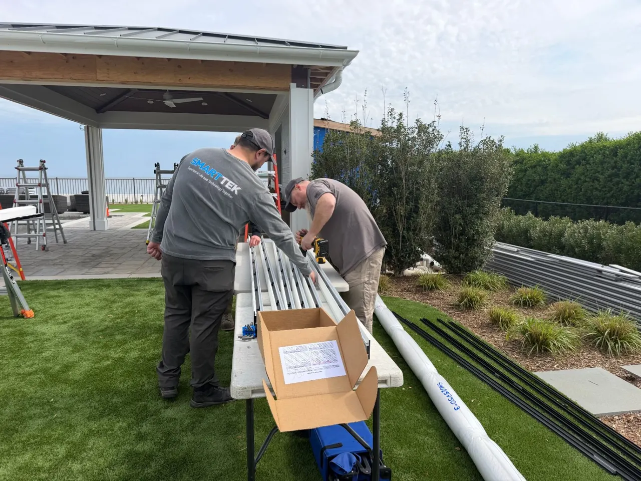 Smart Tek crew measuring and preparing motorized screen tracks at a waterfront pavilion