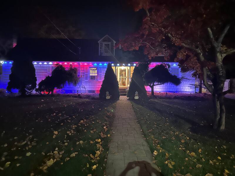 Cape-style home lit red, white, and blue at the rooflines